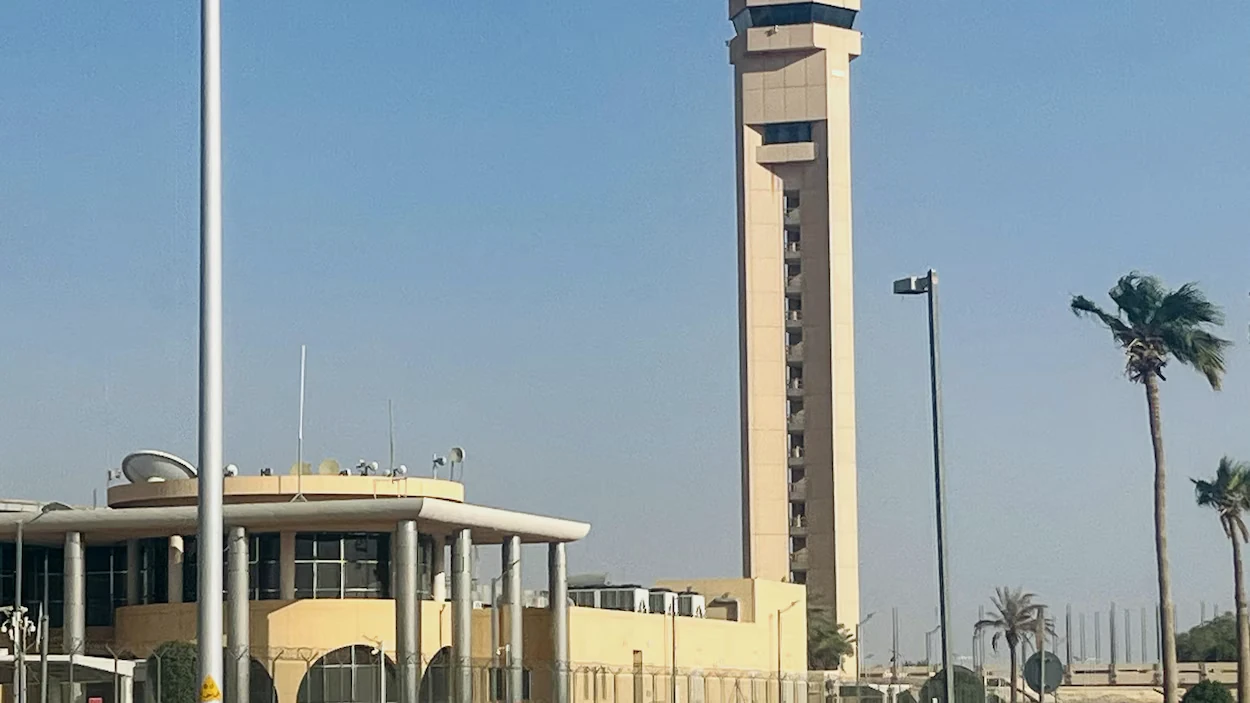 Tour de contrôle d'un aéroport entourée de palmiers sous un ciel dégagé